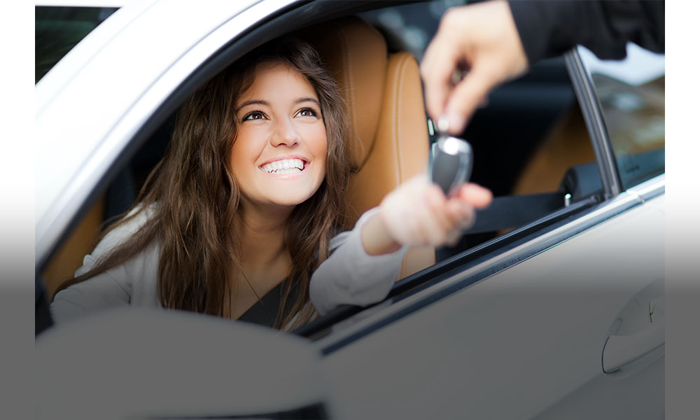 The image shows a smiling women sitting in a car.