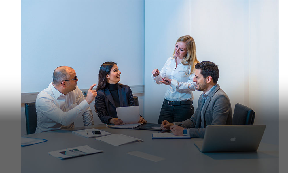 The image shows employees during a meeting in the conference room.