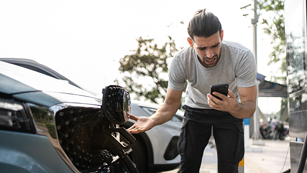 Young man outside car. Dissapointed businessman talking on phone. Broken car charger problem stand besides. Helpless user need help and assistance. Electric car accident. Car trouble