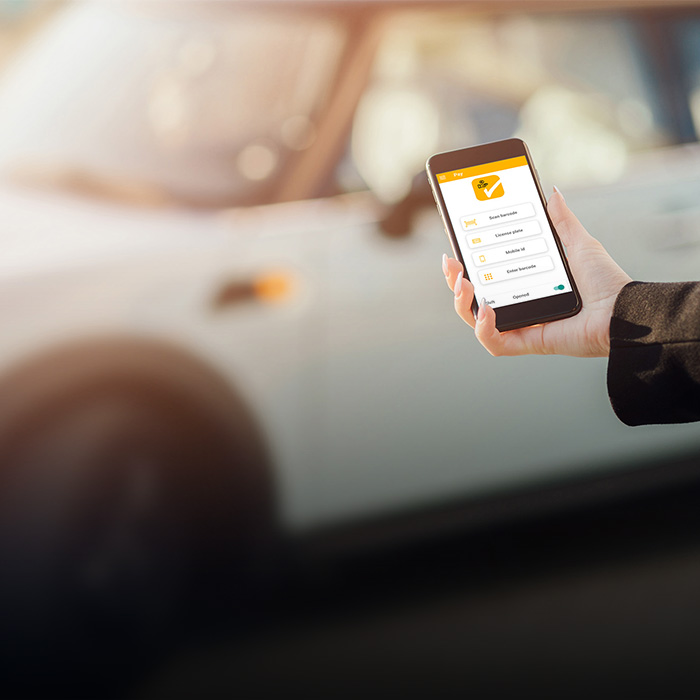 [Translate to Spanish:] Smart Parking Picture Person with Smartphone in front of Car