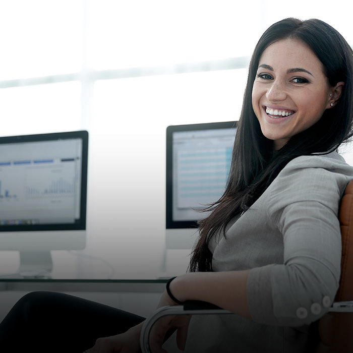 The picture shows a smiling woman at the computer.